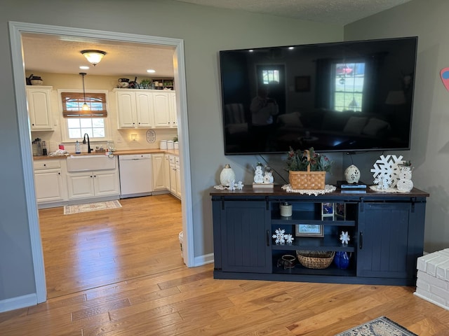 bar featuring light wood-style floors, vaulted ceiling, white dishwasher, a textured ceiling, and a sink