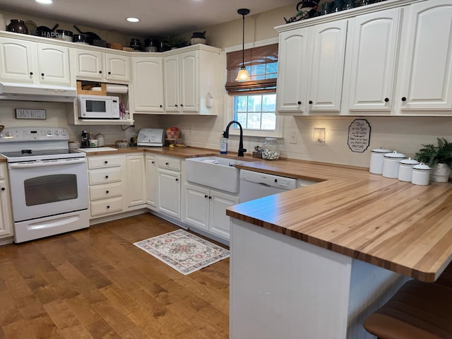 kitchen featuring white appliances, butcher block counters, under cabinet range hood, and a sink