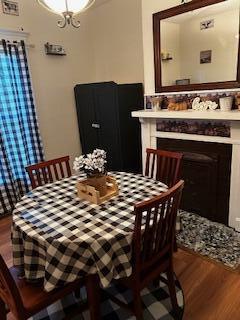 dining room with a fireplace, an inviting chandelier, and wood finished floors