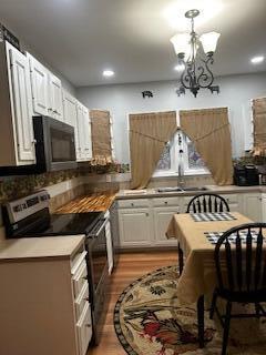 kitchen featuring a chandelier, white cabinets, light wood-style flooring, and stainless steel electric stove