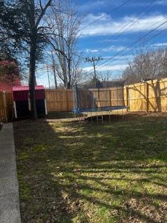 view of yard featuring a trampoline and fence