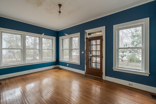 spare room featuring ornamental molding, wood-type flooring, visible vents, and baseboards