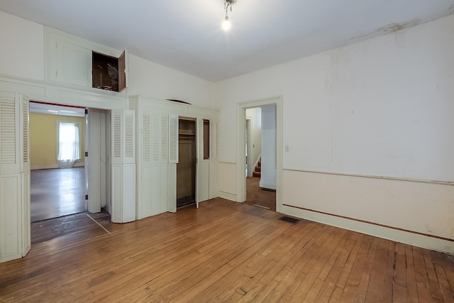 unfurnished bedroom featuring light wood-type flooring, visible vents, and a closet