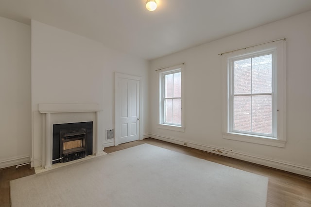 unfurnished living room with visible vents, baseboards, and wood finished floors