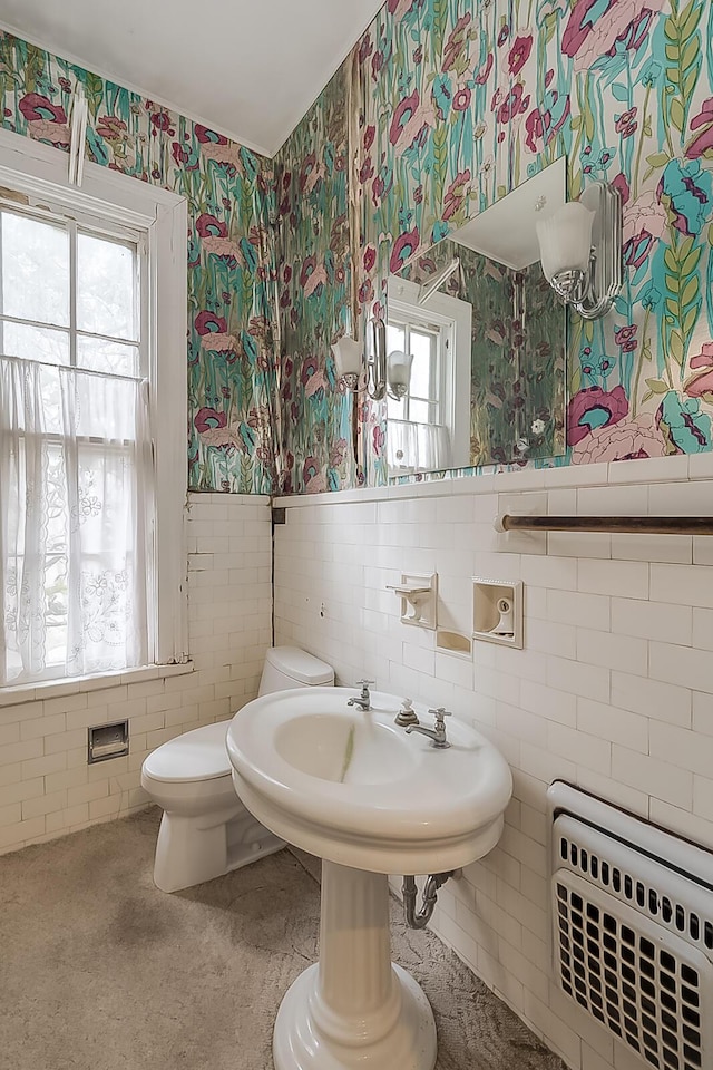 bathroom featuring a wainscoted wall, radiator heating unit, tile walls, and wallpapered walls