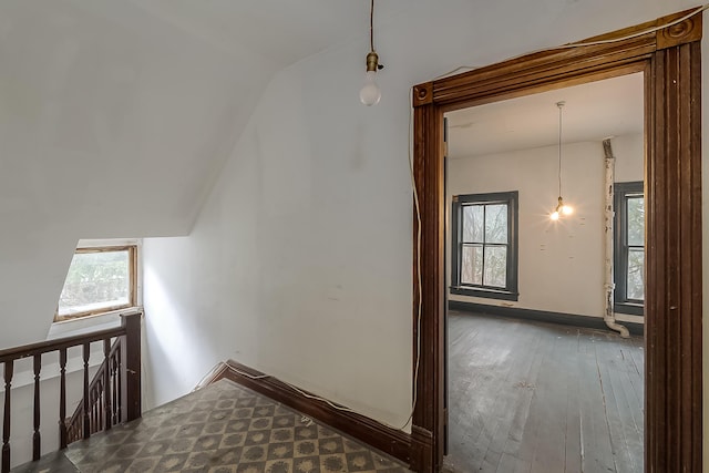 stairs featuring vaulted ceiling, hardwood / wood-style floors, a wealth of natural light, and baseboards