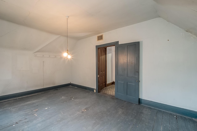 interior space with lofted ceiling, hardwood / wood-style flooring, visible vents, and baseboards