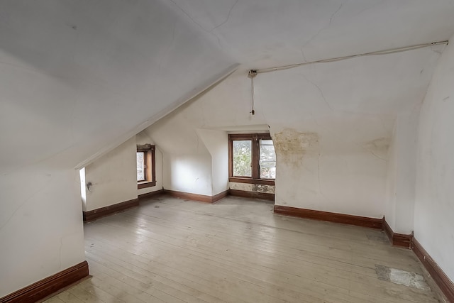 additional living space featuring baseboards, vaulted ceiling, and hardwood / wood-style floors