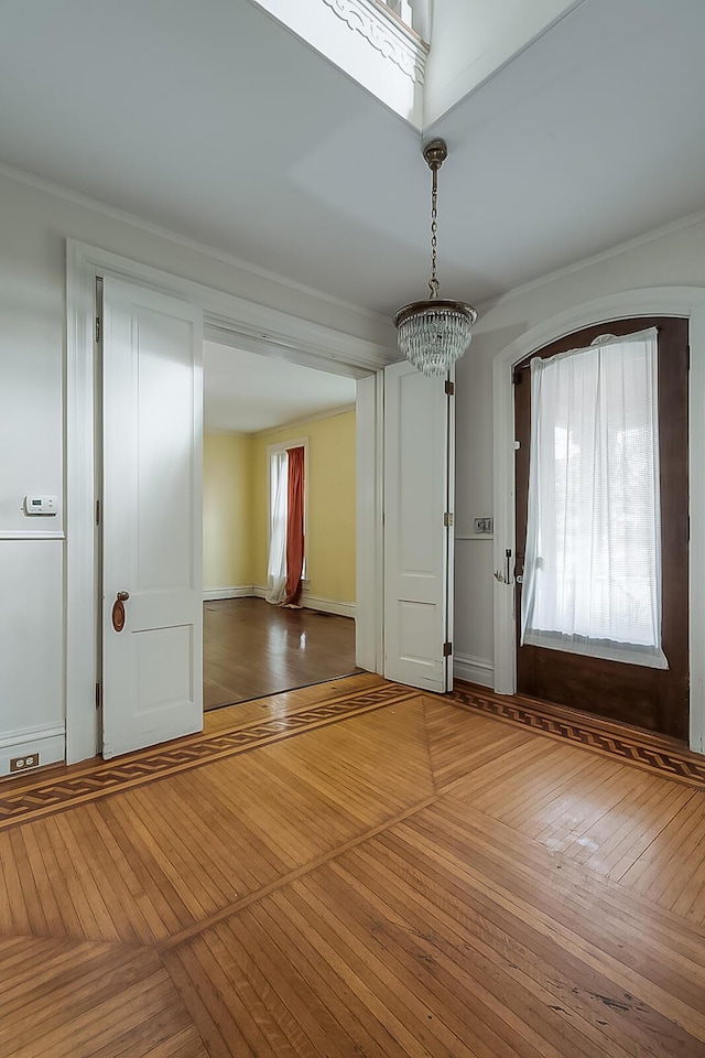 foyer with ornamental molding, wood-type flooring, and baseboards