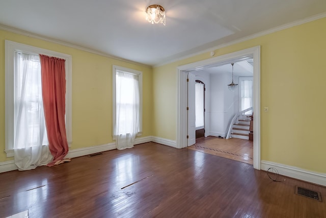 spare room with stairs, ornamental molding, wood finished floors, and visible vents