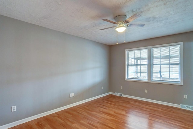 unfurnished room featuring wood finished floors, visible vents, and baseboards