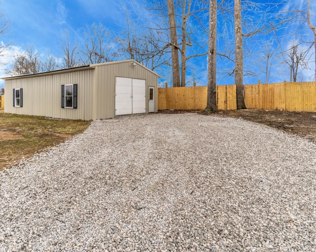 exterior space with an outbuilding, driveway, and fence