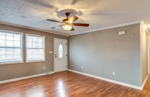 entrance foyer with baseboards, light wood-type flooring, visible vents, and crown molding