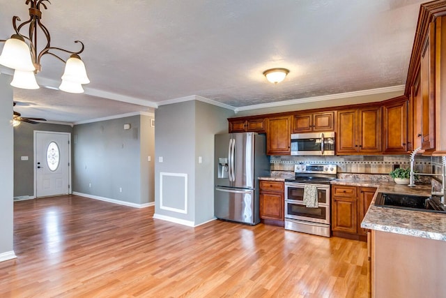 kitchen with stainless steel appliances, decorative backsplash, light wood-style floors, brown cabinetry, and a sink