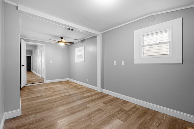 empty room featuring a ceiling fan, baseboards, visible vents, and light wood-type flooring