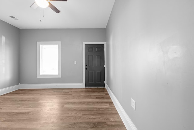 unfurnished room featuring ceiling fan, wood finished floors, visible vents, and baseboards