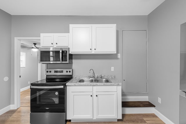 kitchen with white cabinetry, light wood-type flooring, appliances with stainless steel finishes, and a sink