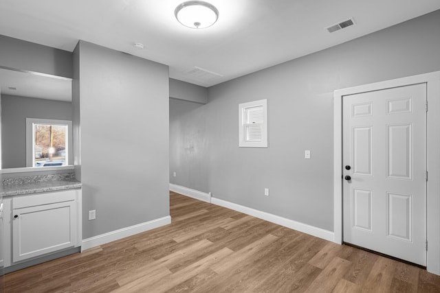 interior space featuring light wood-type flooring, visible vents, and baseboards