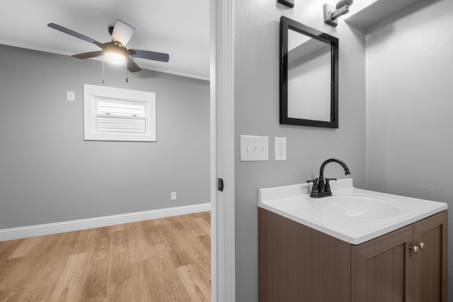 bathroom with ceiling fan, baseboards, wood finished floors, and vanity