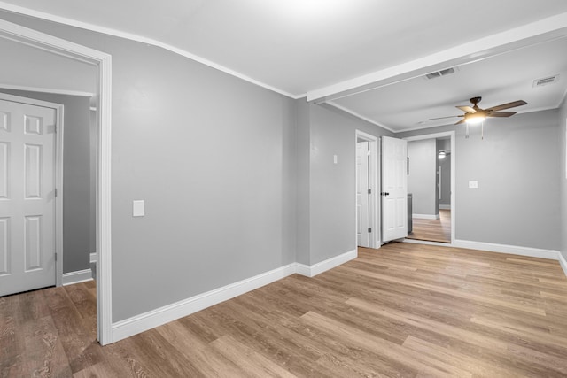 empty room featuring visible vents, light wood finished floors, and ornamental molding