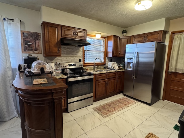 kitchen featuring marble finish floor, under cabinet range hood, a sink, tasteful backsplash, and appliances with stainless steel finishes