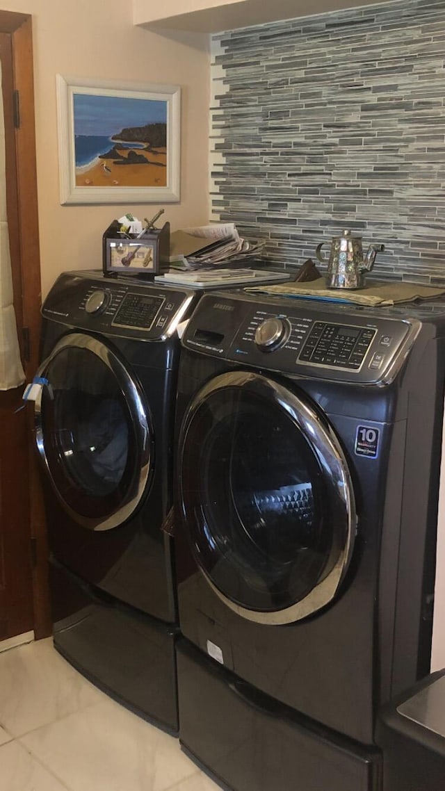 washroom featuring laundry area, light tile patterned floors, and washing machine and clothes dryer