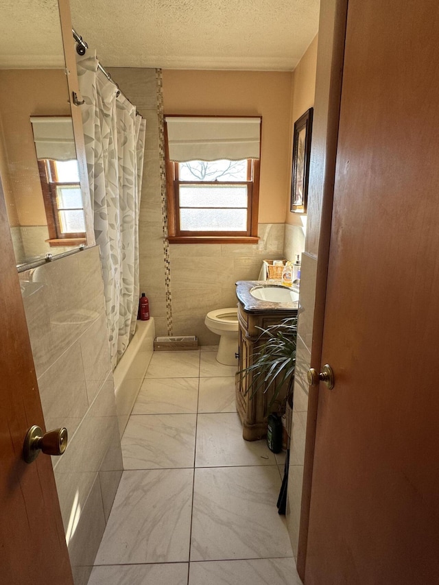 bathroom featuring tile walls, toilet, marble finish floor, a textured ceiling, and vanity