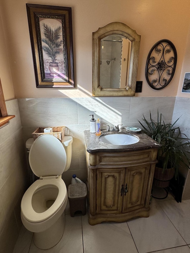 bathroom featuring tile patterned floors, toilet, tile walls, wainscoting, and vanity