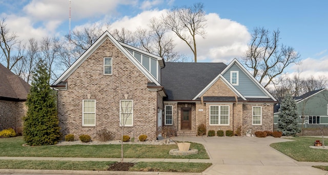 view of front of home with brick siding, a front lawn, and roof with shingles