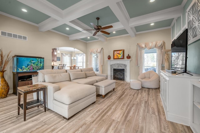 living area featuring light wood-style flooring, beamed ceiling, and visible vents