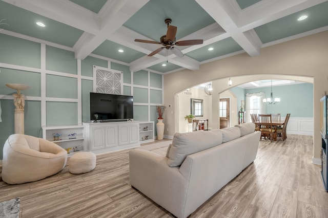 living area with light wood-type flooring, arched walkways, a decorative wall, and beamed ceiling