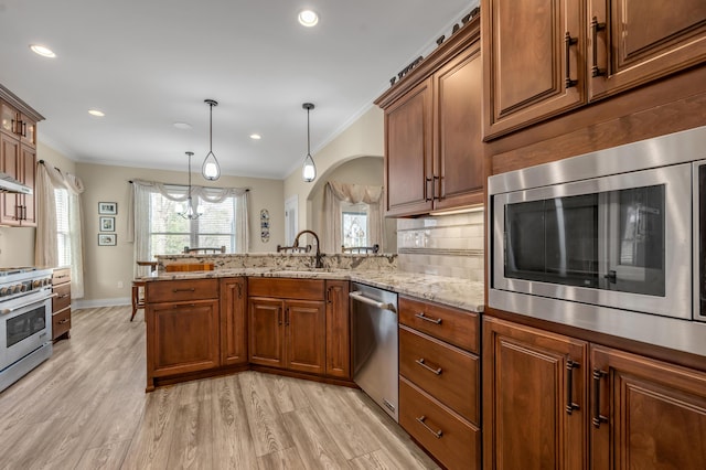 kitchen with tasteful backsplash, ornamental molding, stainless steel appliances, light wood-style floors, and a sink