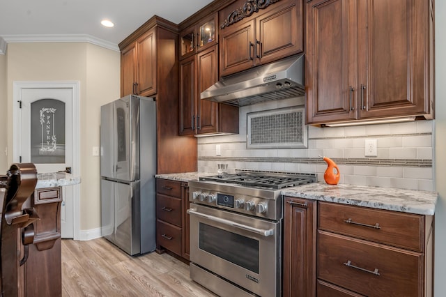 kitchen featuring decorative backsplash, appliances with stainless steel finishes, light stone countertops, crown molding, and under cabinet range hood