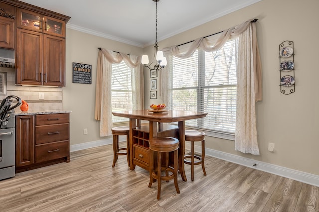 dining room featuring light wood-style floors, baseboards, ornamental molding, and an inviting chandelier