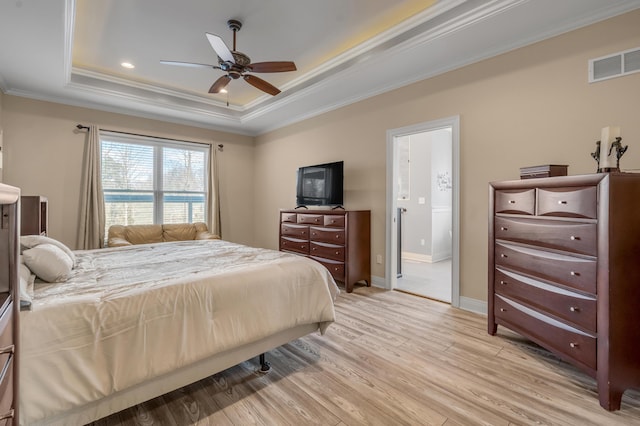 bedroom featuring crown molding, a raised ceiling, visible vents, light wood-type flooring, and baseboards