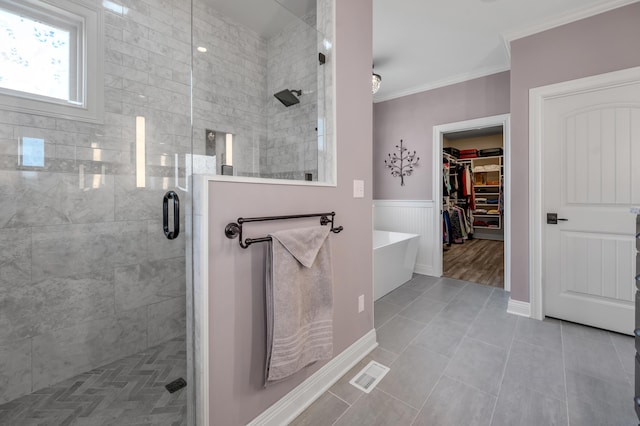 bathroom with a wainscoted wall, visible vents, a spacious closet, a stall shower, and crown molding