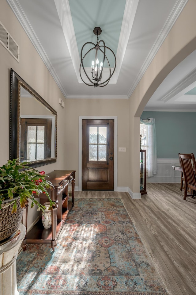 entryway with arched walkways, a tray ceiling, a wealth of natural light, and visible vents