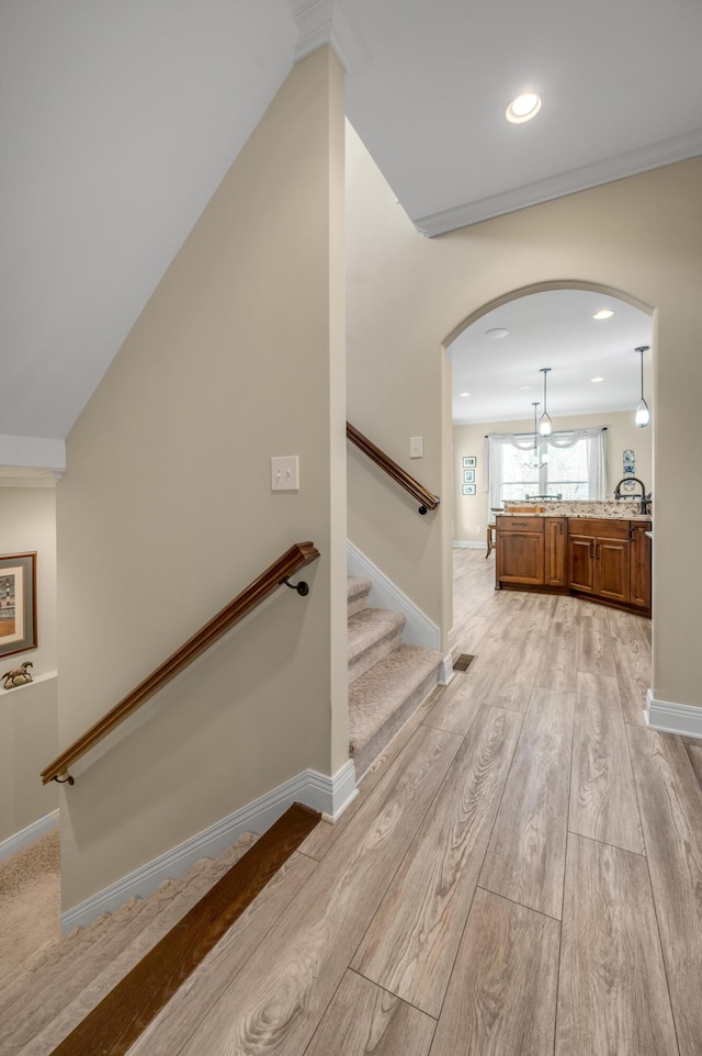 stairs featuring baseboards, arched walkways, wood finished floors, and recessed lighting