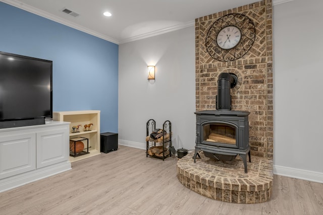 living area with crown molding, visible vents, a wood stove, wood finished floors, and baseboards