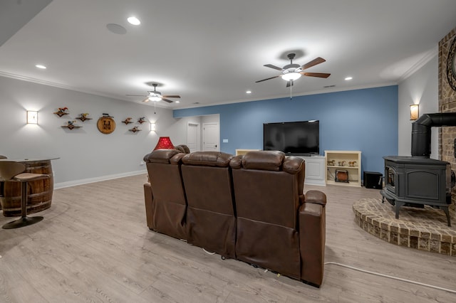 living room featuring baseboards, light wood-style flooring, a ceiling fan, and crown molding