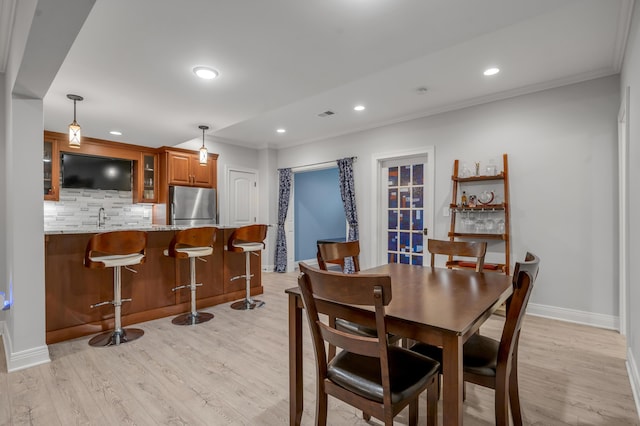 dining space with light wood-type flooring, crown molding, baseboards, and recessed lighting