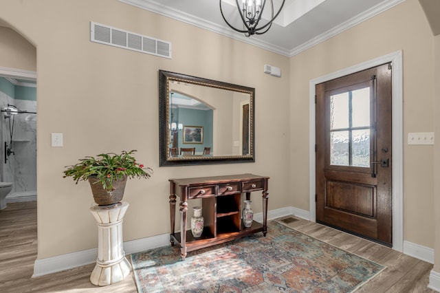 entryway with baseboards, visible vents, wood finished floors, and ornamental molding