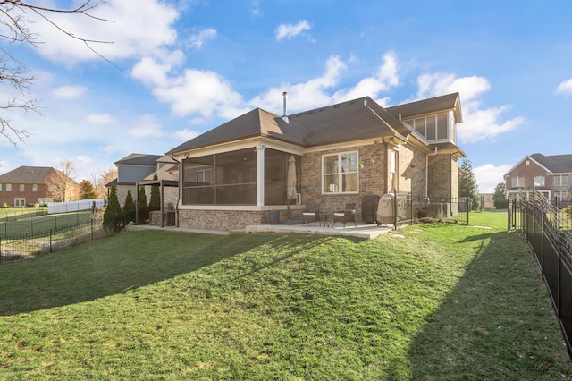 back of property featuring brick siding, a yard, a patio, a sunroom, and a fenced backyard