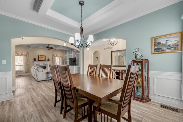 dining room with light wood finished floors, visible vents, arched walkways, a wainscoted wall, and a fireplace