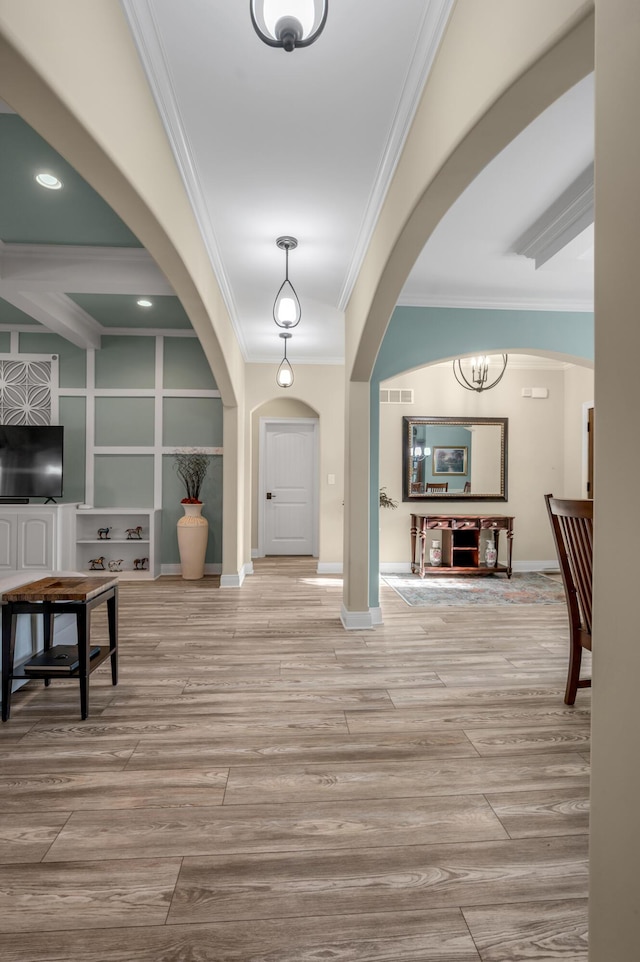 foyer with visible vents, arched walkways, wood finished floors, and ornamental molding