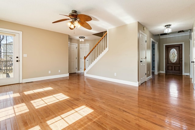 entryway featuring light wood-style floors, ceiling fan, stairway, and baseboards