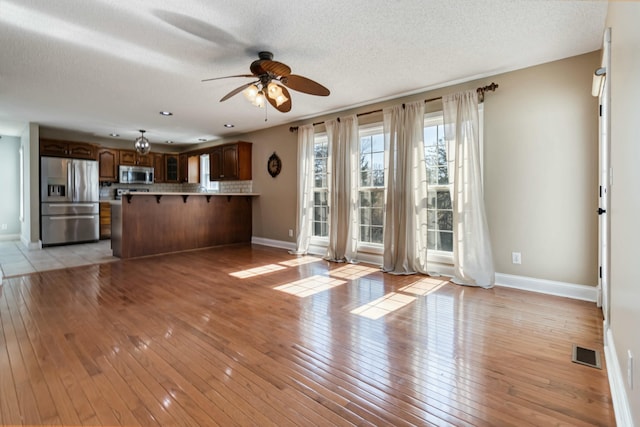 unfurnished living room featuring light wood-style flooring, visible vents, and baseboards