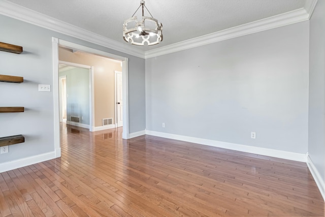 empty room featuring hardwood / wood-style floors, visible vents, crown molding, and an inviting chandelier