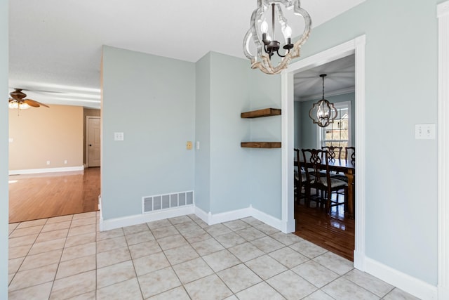 unfurnished dining area featuring light tile patterned floors, ceiling fan with notable chandelier, visible vents, and baseboards