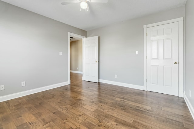 empty room with wood finished floors, a ceiling fan, and baseboards